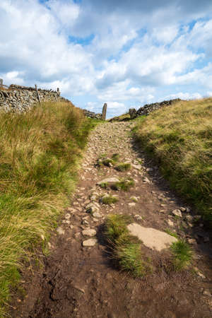 rocky hill walkers foot path with dry stone walls Derbyshire UKの写真素材