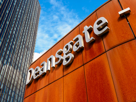Manchester, UK, September 28, 2024: Modern buildings with 'Deansgate' sign on rust-colored facade under blue sky.のeditorial素材