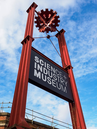 Manchester, UK, September 28, 2024: Red metal sign of the Science and Industry Museum against a blue, cloudy sky.のeditorial素材