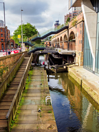 Manchester, UK. September, 28, 2024: Urban canal scene with historic brick architecture and modern bridge.のeditorial素材