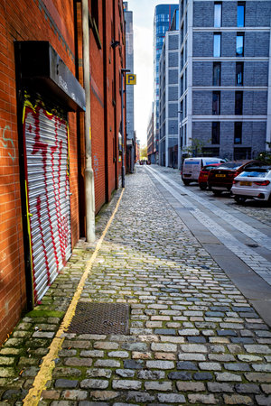 Manchester, UK. October, 26, 2024: Quiet urban alley with cobblestone path and modern buildings.のeditorial素材
