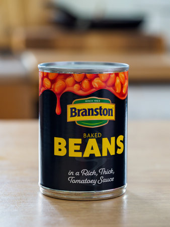 Swinton, Greater Manchester, UK. December 24, 2024: Can of baked beans in rich, thick tomato sauce on a wooden table.のeditorial素材