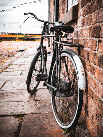 A vintage bicycle leaning against a brick wall on a cobblestone street.の写真素材