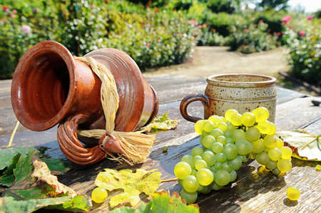 Old ceramic jug, mug and fresh grape on the wooden tableの写真素材