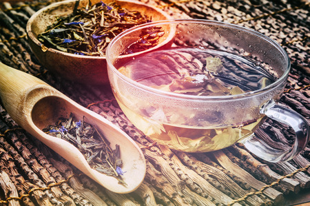 Cup of hot green tea with dry leaves in wooden scoopの写真素材