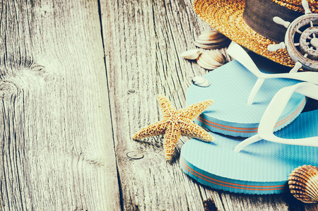 Summer holiday setting with flip flops and straw hat on old wood backgroundの写真素材