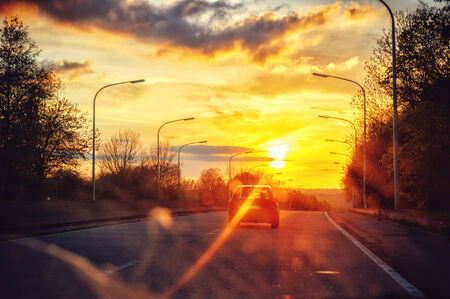 Autumn landscape with  driving car at sunset roadの写真素材