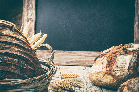 Freshly baked bread in wicker basket with copyspace on blackboardの写真素材
