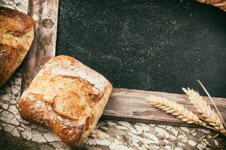 Rustic frame with bread and wheat on wooden backgroundの写真素材