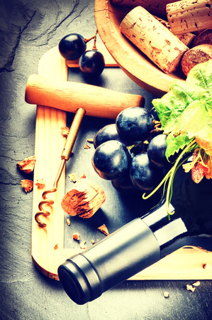 Bottle of red wine with fresh grape and corks in a bowlの写真素材