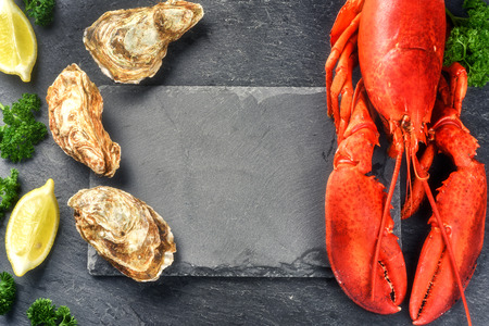 Fine selection of crustacean for dinner. Steamed lobster and oysters on dark backgroundの写真素材