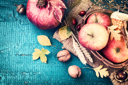 Autumn frame with pomegranate, apple and fall leaves over blue wooden background. Fall background with copy spaceの写真素材