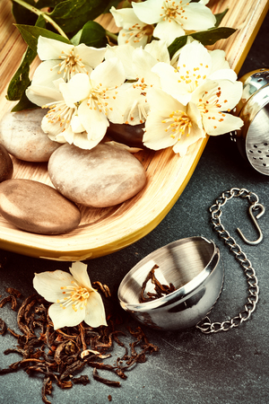 Tea infuser with dry green tea leaves and fresh jasmine flowersの写真素材