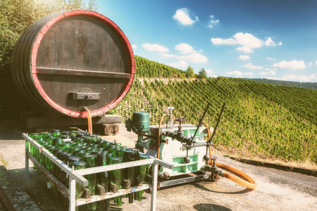 Vintage wine barrel and bottling accessories with vineyards background at sunny fall dayの写真素材