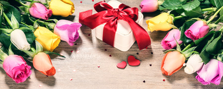 Bouquet of multicolor roses with decorative heart and presents. St Valentine's concept with copy spaceの写真素材