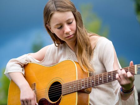 Outdoor portrait of teenage girl playing acoustic guitar