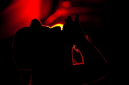 Silhouette of a young adult woman with a bowler hat, drinking a shot against red background of a tent bar in the Sziget music festival in Obudai Island, Budapest, Hungaryの写真素材