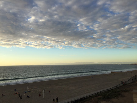 Sunset Over the Tranquil Beach With Playful Clouds Painting the Sky at Duskの写真素材
