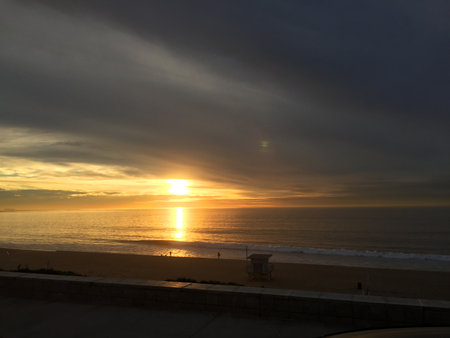 Golden Sunset Reflects on Calm Ocean Waves as Clouds Gracefully Drift Across the Horizonの写真素材