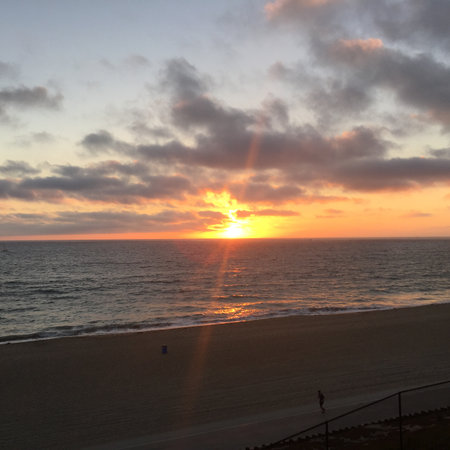 Vibrant Sunset Casts Golden Hues Over Tranquil Ocean Waves at a Serene Beachの写真素材