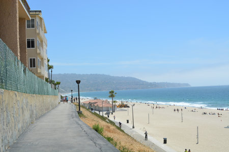Strolling Along the Sunny Beach Walkway With Views of the Ocean and Vibrant Beach Sceneの写真素材