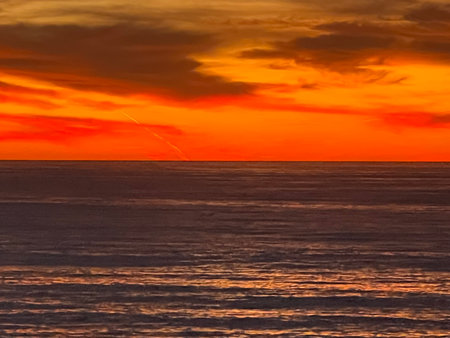 Vibrant Sunset Paints the Ocean Horizon With Warm Hues and Tranquil Waves at Twilightの写真素材