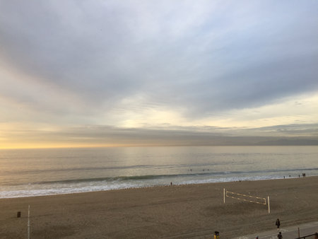 Warm Sunset Light Paints the Ocean Waves and Sandy Beach During a Tranquil Evening by the Shoreの写真素材