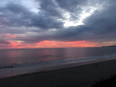 Sunset Paints the Sky With Vibrant Colors Over the Tranquil Ocean Near a Sandy Beachの写真素材