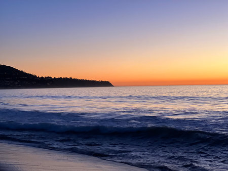 Dusk Descends Over the Tranquil Ocean, Casting a Warm Glow on the Gentle Wavesの写真素材