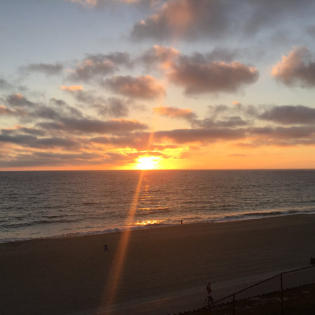 Vibrant Sunset Casts Golden Hues Over Tranquil Ocean Waves at a Serene Beach Locationの写真素材