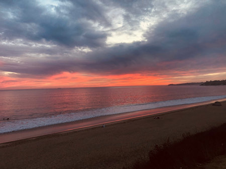 Vibrant Sunset Casts Hues of Orange and Pink Over Serene Ocean Waves at the Beach in Californiaの写真素材