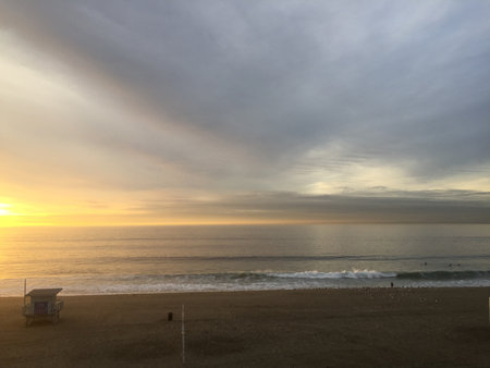 Serene Waves Kiss the Shore Under a Golden Sunrise at a Tranquil Beachの写真素材