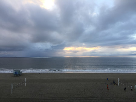 Sunset Over the Calm Beach With Gentle Waves and Volleyball Players Enjoying the Sandy Shore in a Peaceful Evening Settingの写真素材