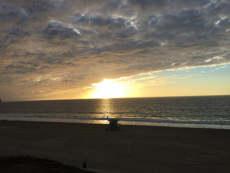 Sunset Over the Serene Beach With Golden Hues Reflecting on the Calm Ocean Wavesの写真素材