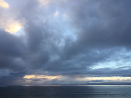 Evening Sky Over Tranquil Ocean Shows Dramatic Clouds and Fading Light Near the Horizon in a Serene Coastal Settingの写真素材