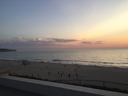 Evening Stroll Along the Shore as the Sun Sets Over the Calm Ocean Wavesの写真素材