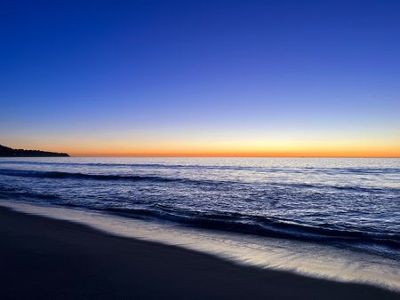 Serene Twilight Over Calm Ocean Waves Near the Shorelineの写真素材