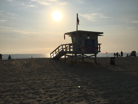 Sunset at the Beach With a Lifeguard Tower Silhouetted Against the Colorful Sky and Soft Sand Belowの写真素材