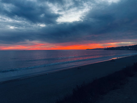 Vivid Sunset Over a Serene Beach Along the Coast During Twilight Hoursの写真素材