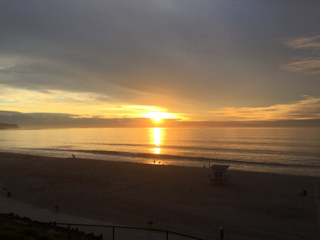Beautiful Sunset Over Calm Ocean Waves at the Beach Creates a Serene Evening Atmosphere With Distant Figures Enjoying the Viewの写真素材