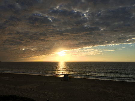 Sunset Over the Tranquil Beach With Dramatic Clouds and Gentle Wavesの写真素材