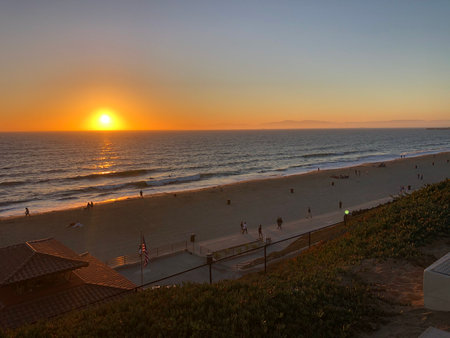 Golden Sunset Over the Ocean With Silhouettes of People Enjoying the Beach in the Late Eveningの写真素材