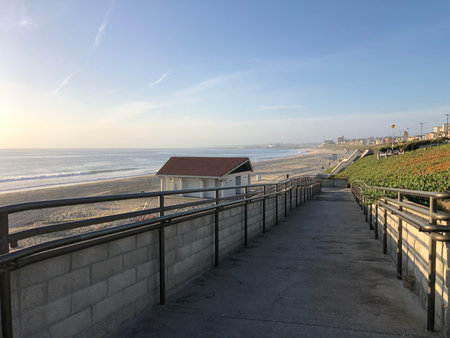 Beautiful Coastal Pathway Leads to a Sunny Beach at Dawn With Gentle Waves and Serene Surroundingsの写真素材