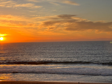 Vibrant Sunset Over Gentle Waves at the Beach, Capturing the Beauty of Nature's Evening Displayの写真素材