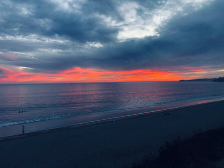 Sunset Over a Calm Beach With Colorful Skies and Gentle Waves on a Peaceful Eveningの写真素材