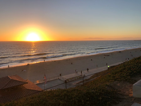 Sunset Over a Serene Beach With Silhouettes of People Enjoying the Evening Sky in Californiaの写真素材