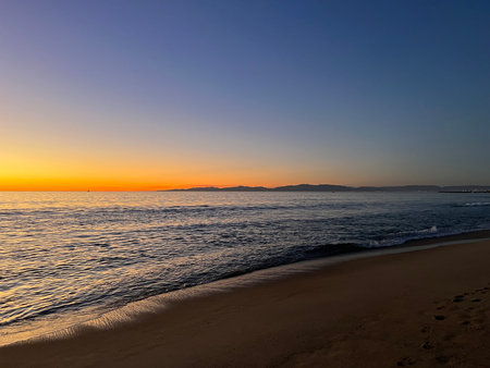 Sunset Paints the Horizon With Vibrant Colors Over the Calm Ocean at the Beach in the Eveningの写真素材