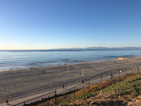 Bright Sunny Day at the Beach With Gentle Waves and Distant Mountains Under a Clear Skyの写真素材