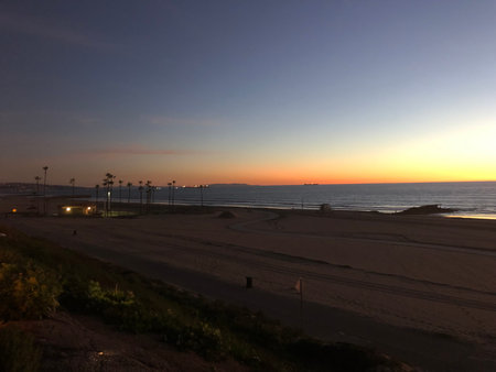 Sunset Over the Beach Illuminates the Sky With Vibrant Colors as Palm Trees Sway Gently in the Evening Breezeの写真素材
