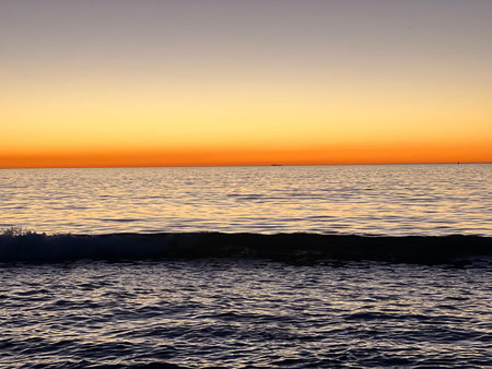 Captivating Sunset Over Tranquil Ocean Waves Creating a Serene Atmosphere at Duskの写真素材